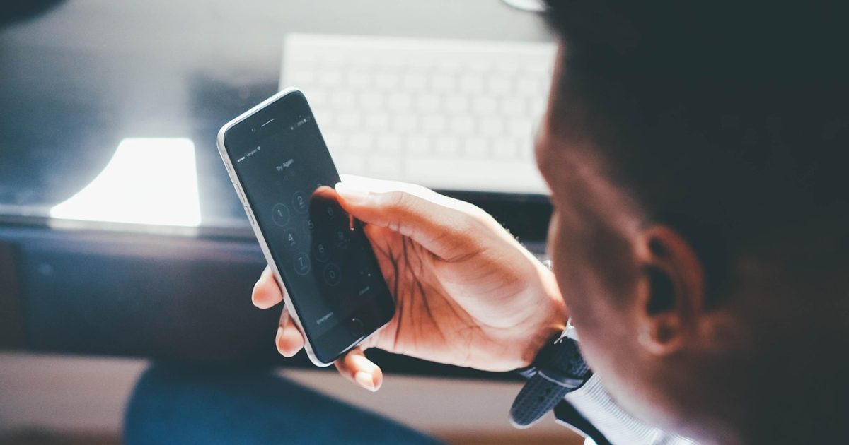 米兰体育app 主界面在手机屏幕上居中展示，深色导航栏与米金色数据卡片分层排列，桌面环境整洁明亮